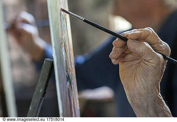 close-up of elderly hand painting with paintbrush