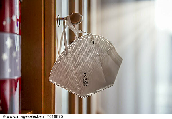 Close-up of face mask hanging on knob at home