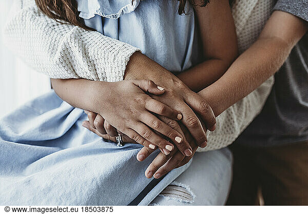 Close up of family's hands intertwined in studio