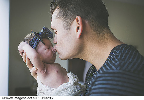 Close-up of father kissing newborn daughter at home