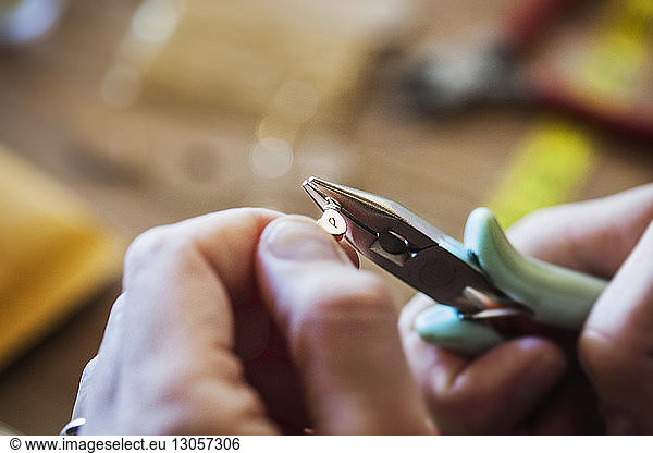 Close-up of female artist using pliers while making jewelry in workshop
