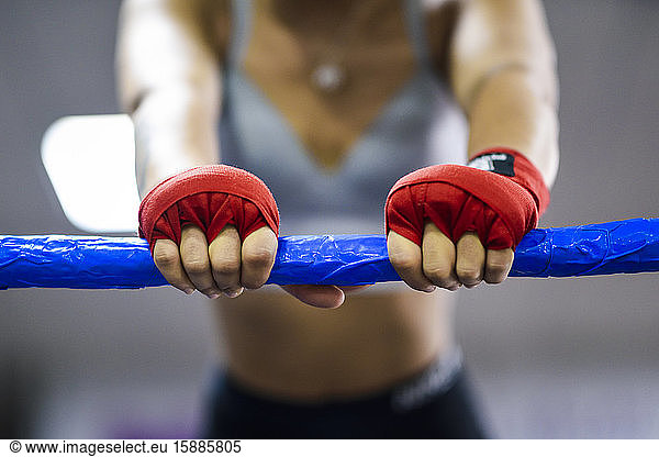 Close-up of female boxer in boxing ring leaning on rope