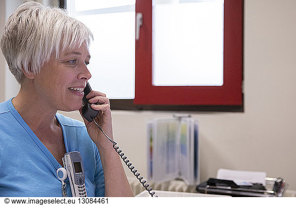 Close-up of female doctor talking on telephone while sitting in hospital