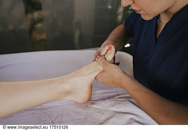 Close-up of female therapist giving foot massage to woman on table in health spa