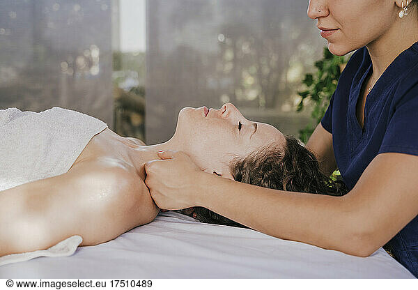 Close-up of female therapist massaging customer's neck on table in health spa