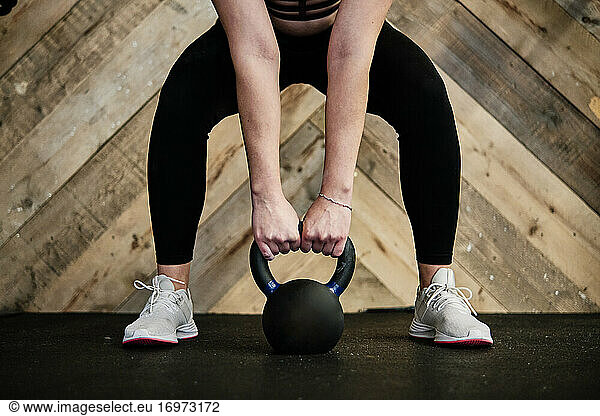 close-up of fit woman in exercise gear lifting a kettlebell at the gym