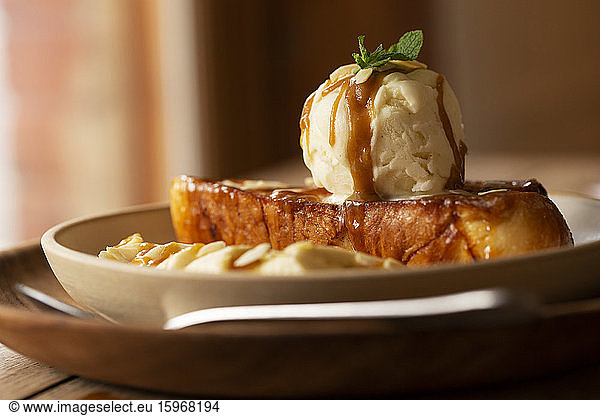Close up of French toast with sliced banana and ice cream in a cafe.