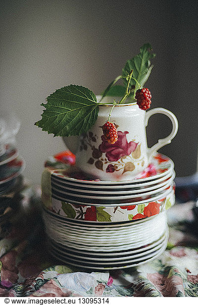 Close-up of fresh raspberries in teapot on stacked saucers