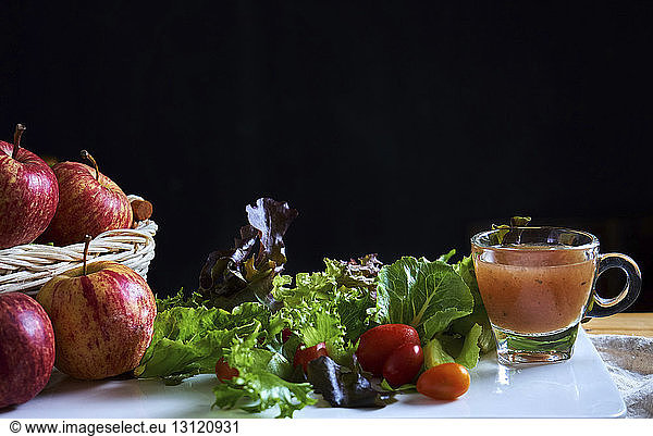Close-up of fruits and vegetables with dip on table against black background