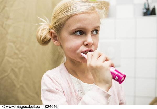 Close-up of girl brushing teeth in bathroom