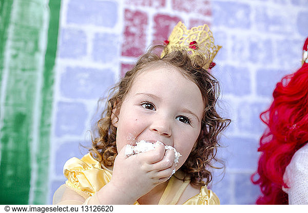 Close-up of girl eating cake during princess party