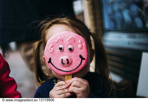 Close-up of girl hiding face with candy