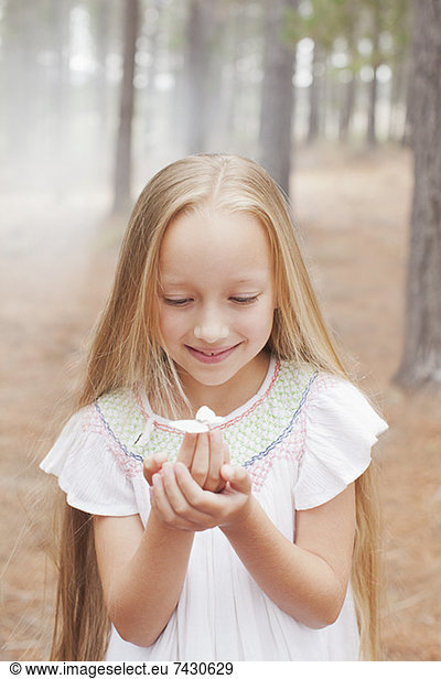 Close up of girl holding butterfly in woods