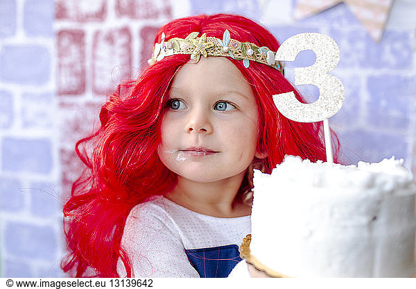 Close-up of girl holding cake with number 3 during princess party