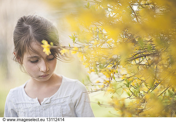 Close-up of girl standing by flowering plant
