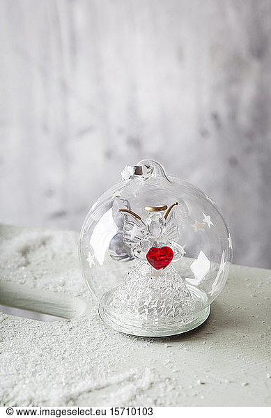 Close up of glass Christmas bauble with angel figurine inside and red heart