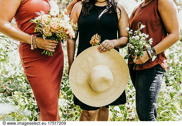Close up of group of women holding flowers and large sun hat