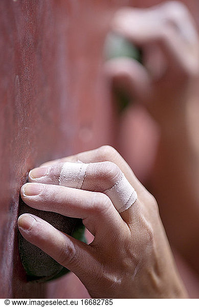 close up of hand holding on to handhold at indoor climbing gym