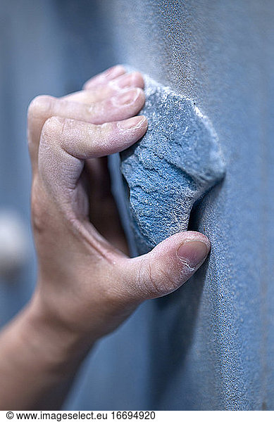 close up of hand holding on to handhold at indoor climbing gym