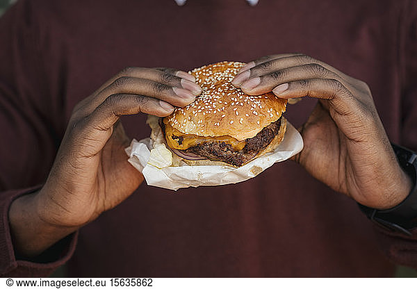 Close-up of hands  holding cheeseburger