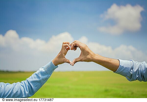 Close up of hands of a couple making a heart shape with hands  hands of a couple in love in the field making a heart shape  couple in the field making a heart shape with hands