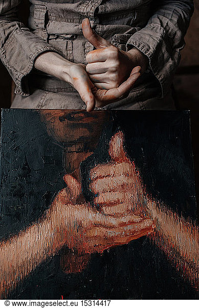 Close-up of hands of a female painter in her studio with a painting of hands
