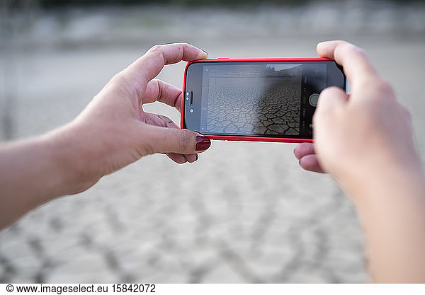 Close up of hands taking a photo with cellphone of landscape.