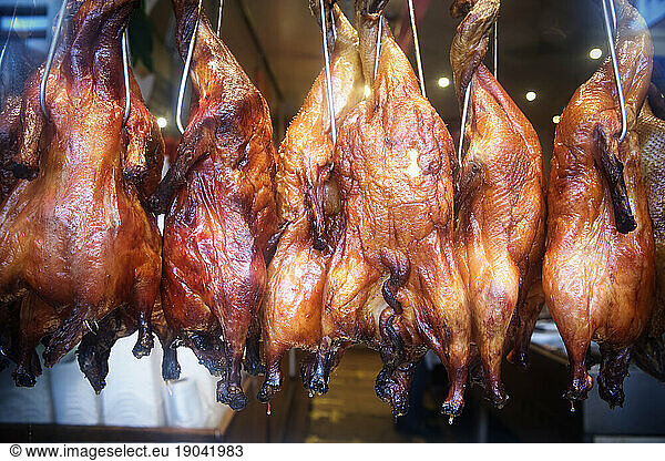 Close up of hanging roasted chickens in a store front window  Chinatown  San Francisco  CA.