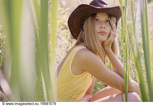 Close-up of hippie woman in swimsuit and cowboy hat in reeds at sunset