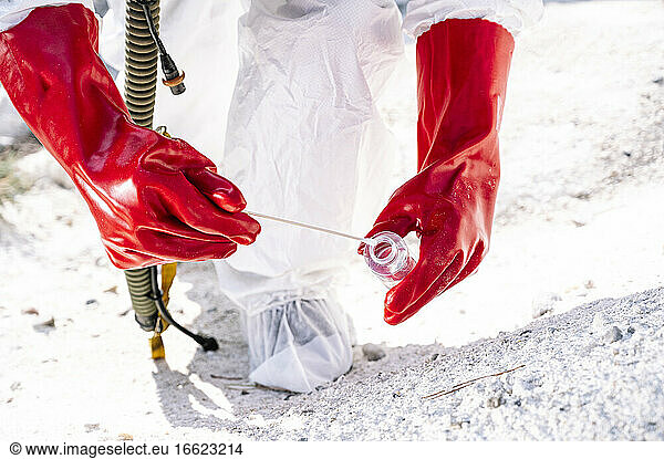Close-up of male astronaut collecting samples on snow covered land