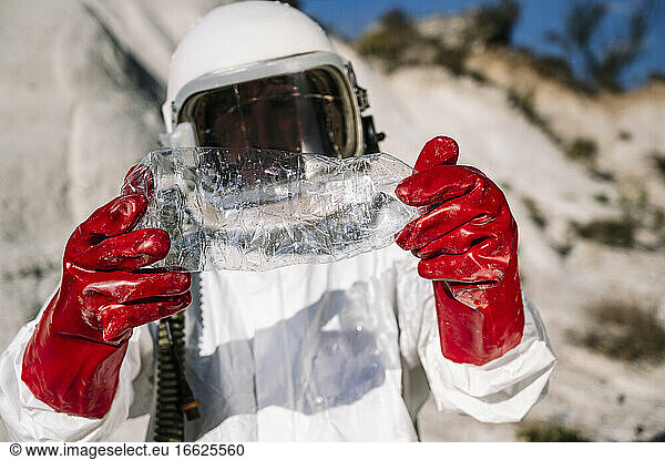 Close-up of male astronaut holding plastic bottle while standing on other planet