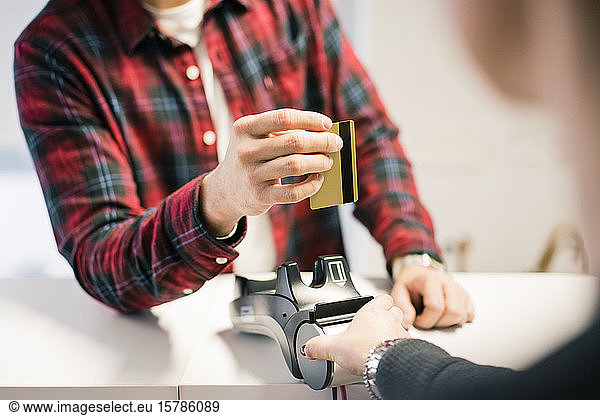 Close-up of man paying with credit card at the counter of a shop