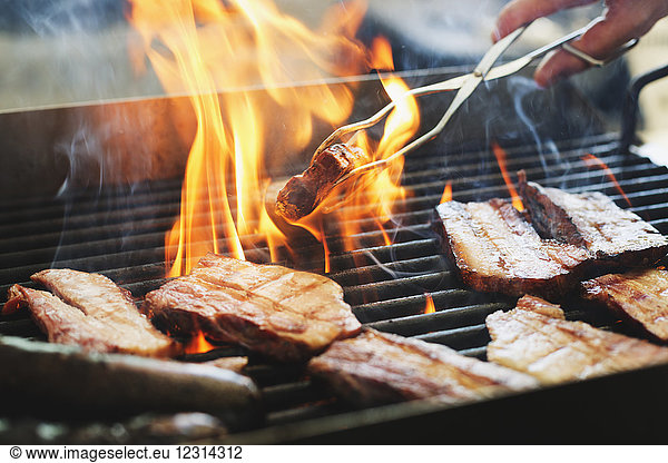 Close-up of man preparing meat on grill