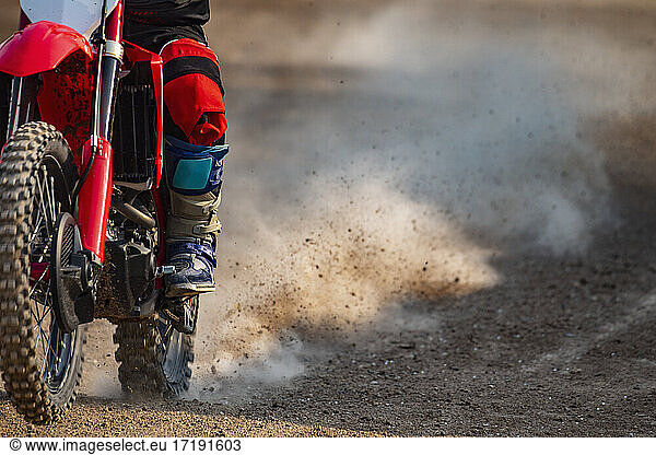 close up of man riding his off road motorcycle on dirt race course