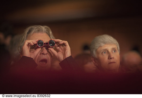 Close up of man using opera glasses in theater