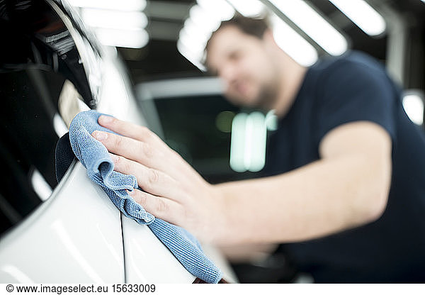 Close-up of man working in modern car factory wiping finished car
