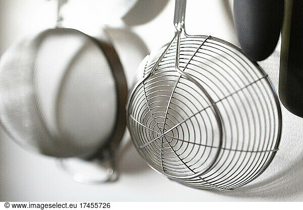Close-Up of Metal Strainer Hanging on White Kitchen Wall
