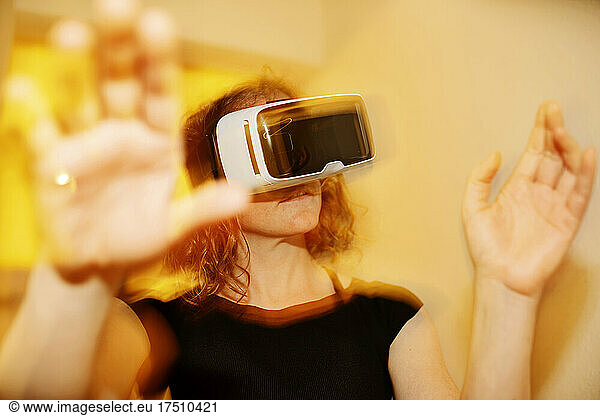 Close-up of mid adult woman looking through virtual reality simulator at home