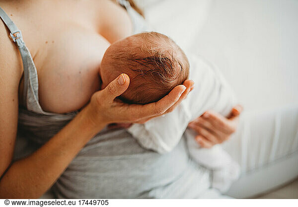 Close up of mom holding newborn's head while breastfeeding