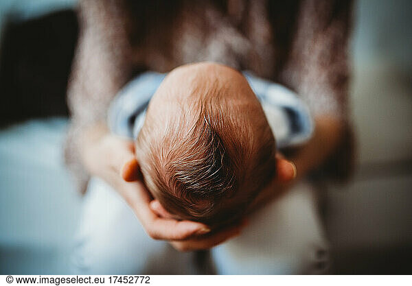 Close up of mom's hands holding baby newborn head full of hair