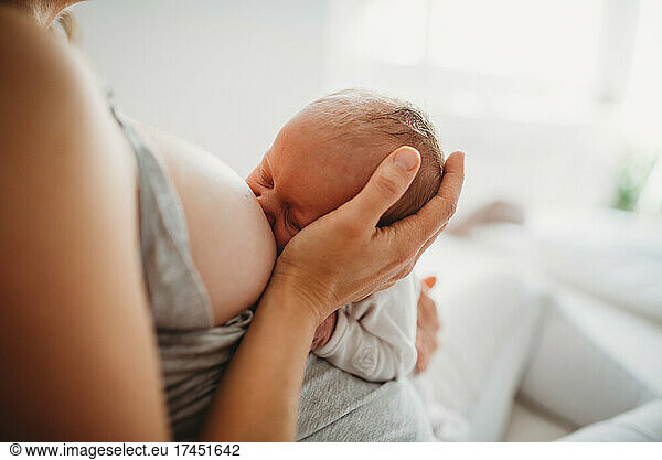 Close up of mother holding baby's head while breastfeeding