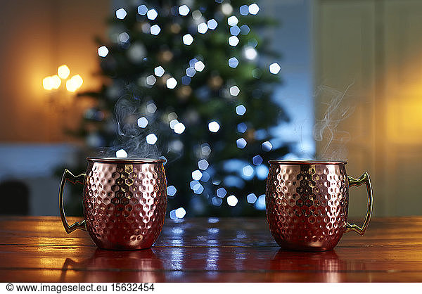 Close-up of mulled wine served on wooden table against illuminated Christmas tree at home