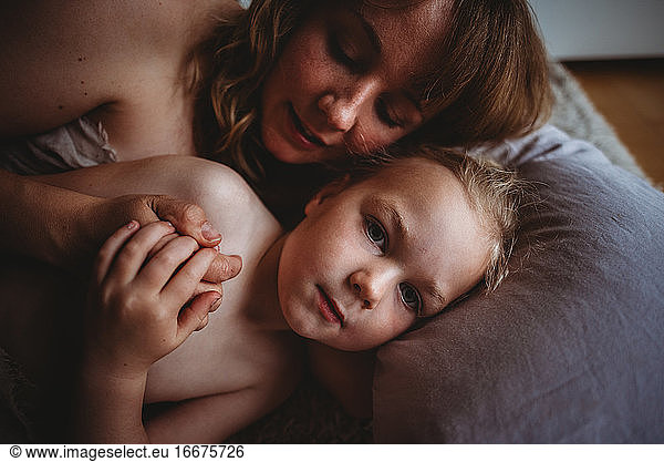 close up of mum hugging her daughter in bed holding hands