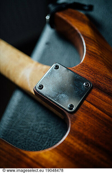 Close up of neck plate on wooden electric guitar.