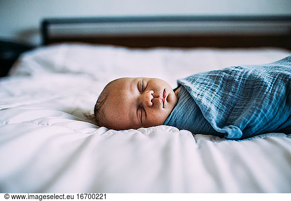 Close up of newborn sleeping on bed alone