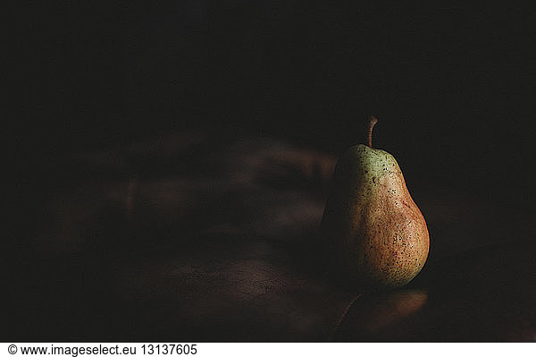Close-up of pear on table against black background