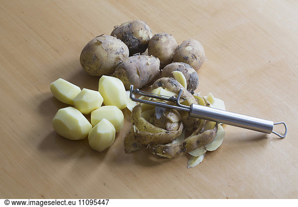 Close-up of peeled and raw potatoes with peeler on table  Freiburg im breisgau  Baden-württemberg  Germany