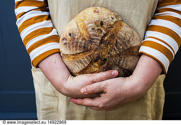Close up of person holding a freshly baked round loaf of bread.