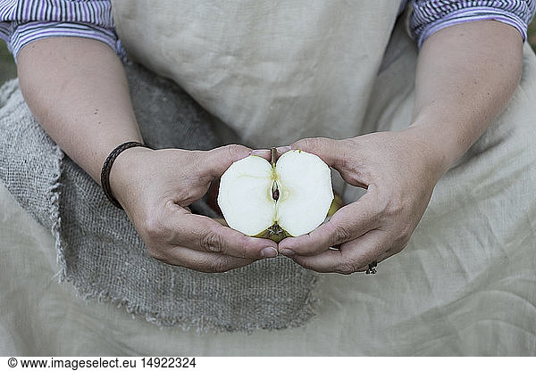 Close up of person holding apple cut in half.