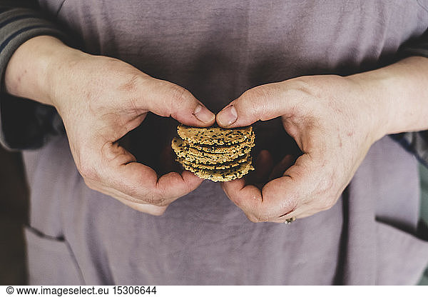 Close up of person holding small stack of freshly baked seeded crackers.